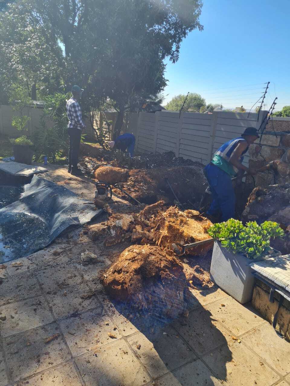 One standing and two workers wearing blue working suits, one wearing a reflector